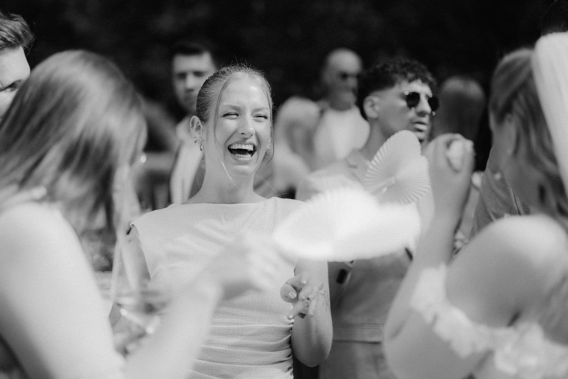 Schwarzweißaufnahme vom Sektempfang: Lachen zwischen den Hochzeitsgästen